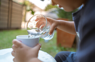 Little child pouring drinking water into a glass