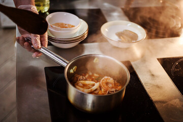 Close up view of seafood soup preparation process. Tom Yam is boiling in the sauce pan on the induction stove. Mediterranean and asian traditional meal.