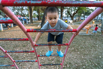 cute little Asian boy climbing ladder in public kid playground