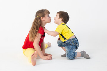 cute boy and girl in bright clothes kissing on a white background