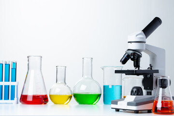 Lab microscope with laboratory glassware on desk