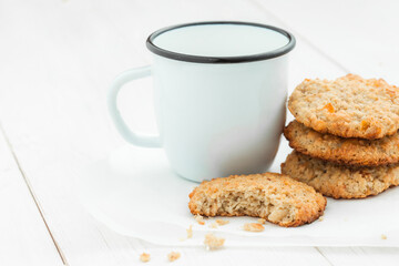 Cookies and a cup on a light wooden table on a white background closeup.