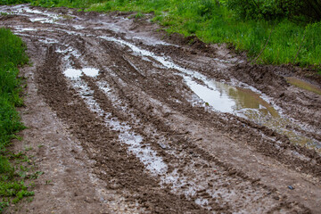 dirty clay mud road with puddles and tire tracks - closeup with selective focus and linear...