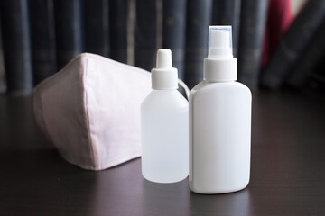 Facemask on Dark Background with two bottles of sanitizers A respirator protects the wearer from inhaling hazardous atmospheres, including fumes, vapors, gases and particulate matter such as dusts