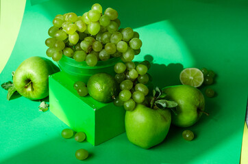 Collection of green fruits on green background. Apple, grapes and lime.