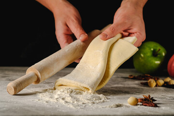 The process of making apple pie. Dough on a dark background.Baker holds the dough in his hands.