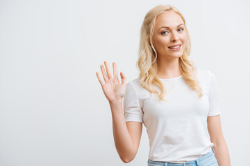 happy beautiful woman waving hand while looking at camera isolated on white