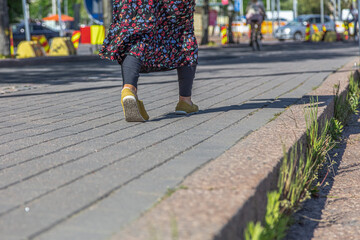 A woman is walking on a road in the city. Cropped photo