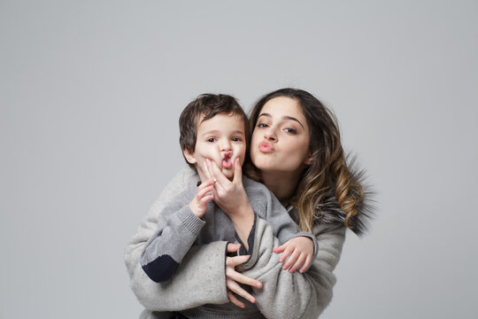 brother and sister pose in a playful setting in this conceptual image on grey background. Sibling friendship concept. Children of different ages.