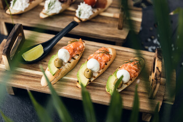 Italian cuisine, antipasti and tapas. Bruschetta of baguette and cottage cheese, tomato, salmon capers, pesto. Serving dishes in a restaurant in white plate.