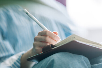 Beautiful brunette with a short haircut works in the home office on a blue background. Typing on a laptop, calling on the phone, transferring documents, making notes, drinking coffee from a mug.