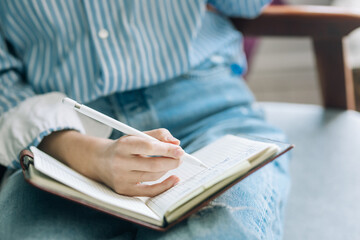 Beautiful brunette with a short haircut works in the home office on a blue background. Typing on a laptop, calling on the phone, transferring documents, making notes, drinking coffee from a mug.