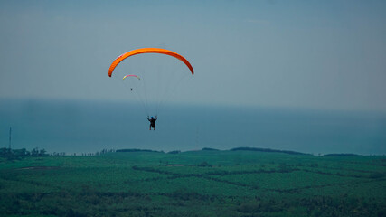 Paralayang terbang melayang di langit biru.