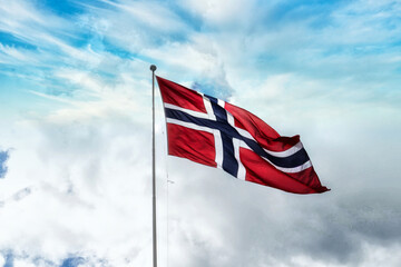 Norwegian flag against blue cloudy sky