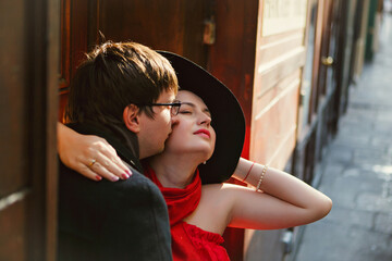 man and woman in red and hat hugging on narrow European streets. romantic.