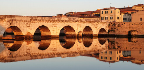 Bridge of Tiberius in Rimini, Italy at sunset. Panorama of a colorful sunset on the background of...