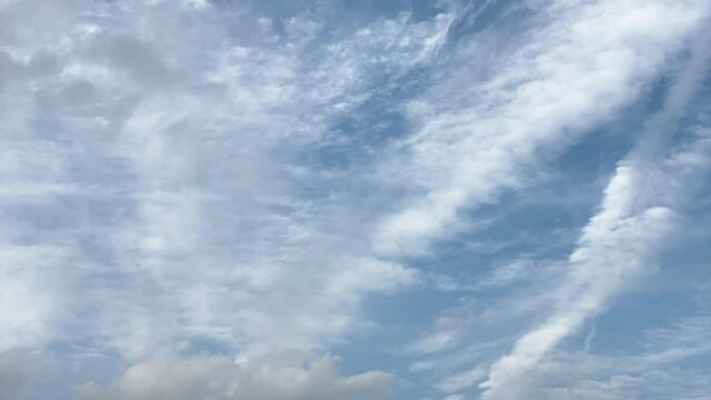 青空を流れる白い雲と通過する飛行機雲 タイムラプス
