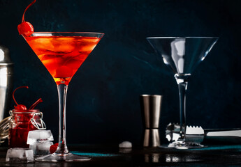 Manhattan alcoholic cocktail with bourbon, red vemuth, bitter, ice and cocktail cherry in glass, night mood image, copy space