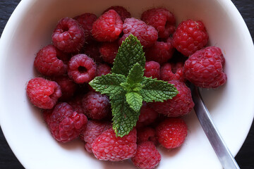 Photography of raspberries in white ceramic bowl with mint bunch and a stainless steel spoon for food illustrations