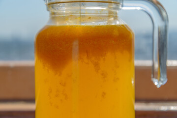 Glass carafe with compote from sea-buckthorn in the kitchen. Home made. Shallow depth of field.