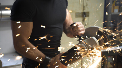 Worker man cutting metal part with angle grinder , closeup muscular arm, cutting tube	

