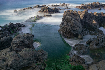Volcanic rocks in Atlantic ocean, long exposure photography, rocks with green moss , Puerto de la Cruz coastline, Tenerife, Canary islands, Spain