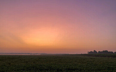 Colorful glowing sunrise over a countryside farming area, creating an idyllic scenic landscape