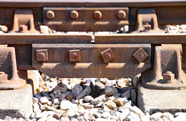 Close up of rusty railway track showing the nuts and bolts of the fishplate which joins sections of track.