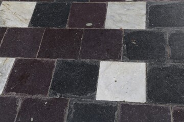 A closeup view of a scratched marble and slate tiled entrance floor in an old building.