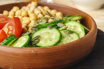 Clay plate of chickpeas and cut cucumbers and tomatoes. Healthy eating