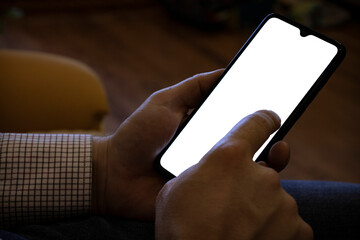 Phone in a male hand with a white screen. Background is dark, mockup phone.