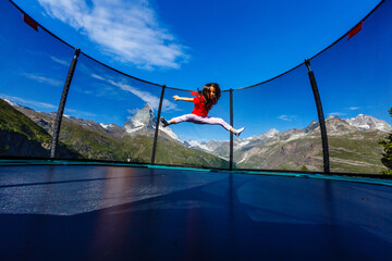 little girl on a trampoline in the mountains, Alps
