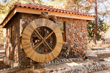 traditional stone house with tiled roof and wooden water mill on a sunny day