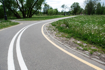 Turn of bike path in spring park. Empty road.