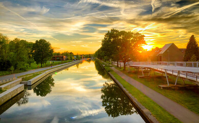Fototapeta premium Dramatic sunset over a body of water surrounded by trees. High quality photo