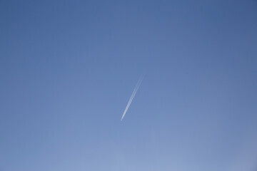 Airplanes leaving diagonal trace on a clear blue sky. Plane trail concept, traveling environmental issues