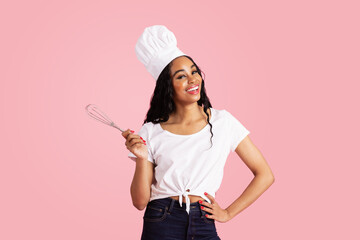 Portrait of a smiling young female chef with whisker looking at camera, against pink studio background