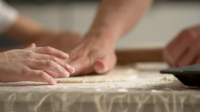 Children cooks pizza. Boy and girl having fun with father. Prepering ingredients for pizza. Roll out the dough with a rolling pin