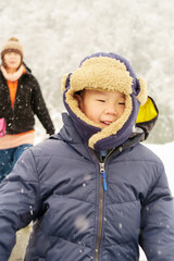 A asian boy is walking on the snowy place in front of mother. The place is in Kyoto, Osaka, Japan