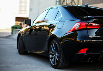 Modern black car parking on the road. Close up. Headlights detail.