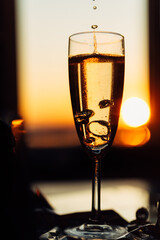 glass of champagne with splashing bubbles in the setting sun