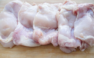 Skinless chicken thigh filet on a wooden surface. Ingredient, fresh meat for cooking. Parts of chicken, protein. Dietary meat of domestic chickens. Thigh fillet on a blackboard