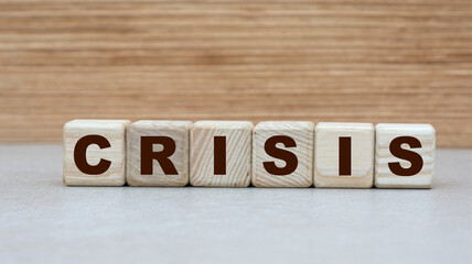 concept of the word CRISIS on cubes on a wooden background