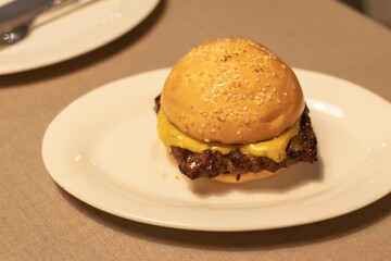Delicious cheese burger; beef with melting of cheese in warm light at restaurant. 
