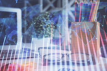 Financial chart hologram with glasses on the table background. Concept of business. Double exposure.