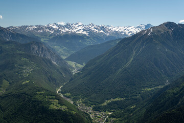 Alpine mountains, meadows and forests on a background of blue sky with clouds.