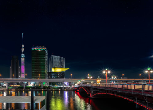 Night view of the Azuma bridge on Sumida river leading to the Tokyo Skytree and Olympic golden flame shape sculpture of the Asahi Beer Headquarter Building in Asakusa.