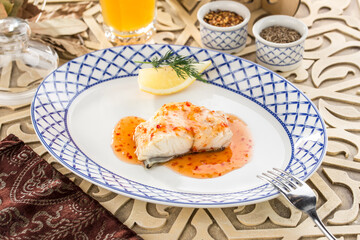 Fried white fish with chili pepper sauce on oriental wooden table