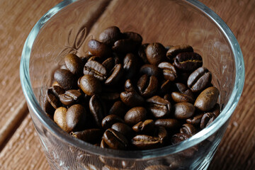 white cup and coffee beans scattered on wooden surface. food and beverage concept