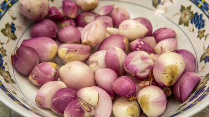 Close up view of full group raw small red onions after peeling the skin for cooking ingredient in a bowl. Selective focus.